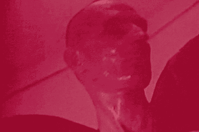 a close up of a man 's face with a red background .
