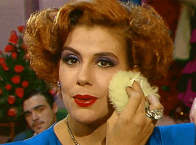 a woman with red hair and a ring on her finger holds a white furry object to her face