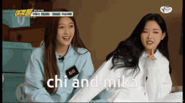 two asian girls are sitting next to each other and the words chi and mika are visible