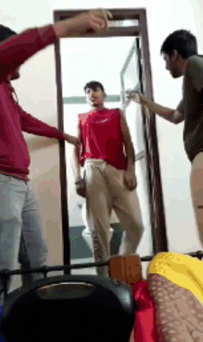 a man in a red shirt is standing in front of a mirror with two other men