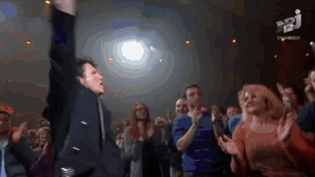 a man in a suit is dancing in front of a crowd with the letters api on the bottom