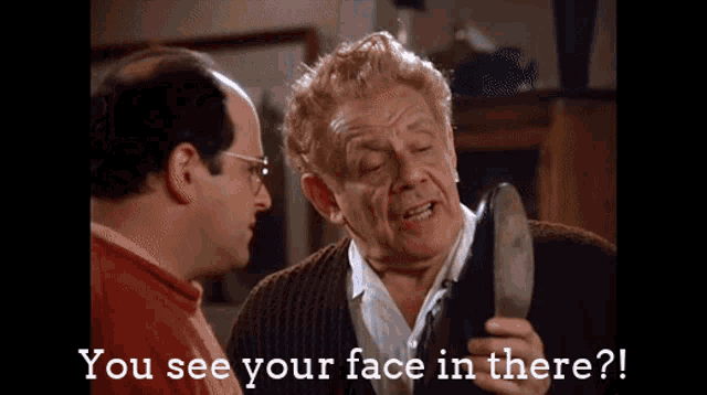 a man is holding a shoe and talking to another man who says you see your face in there