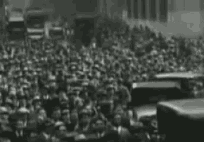a black and white photo of a crowd of people gathered in a city street .