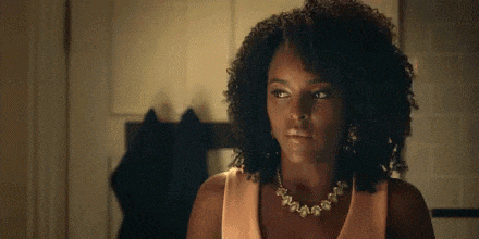 the woman is wearing a necklace and earrings and looking at the camera .