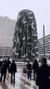 a group of people are standing in front of a celsius sculpture