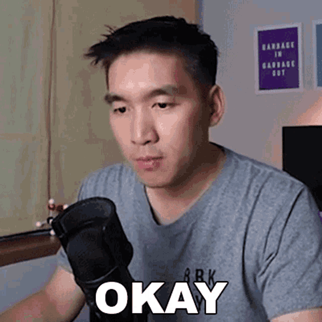 a man sitting in front of a microphone with the word okay written on his face