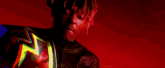 a man with dreadlocks is standing in front of a fire and a lightning bolt .