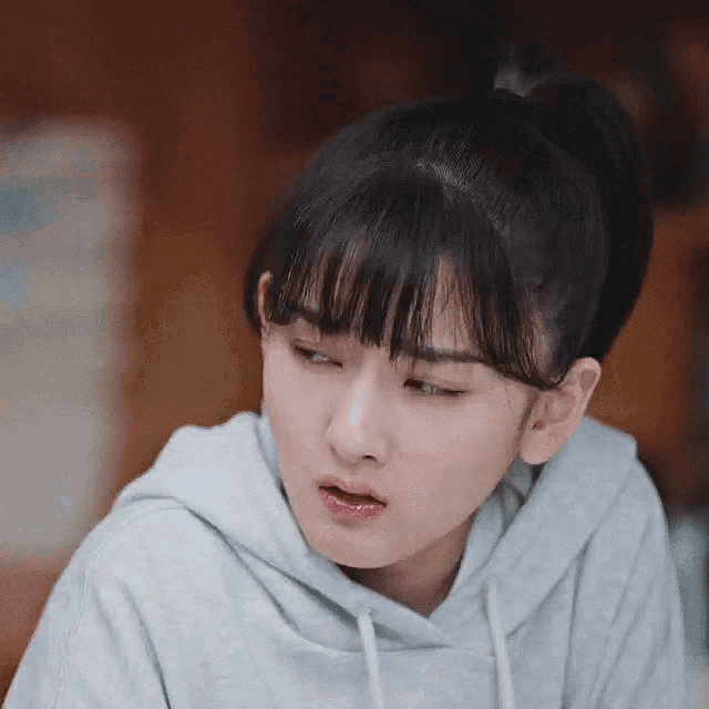 a close up of a woman wearing a hoodie and a ponytail .