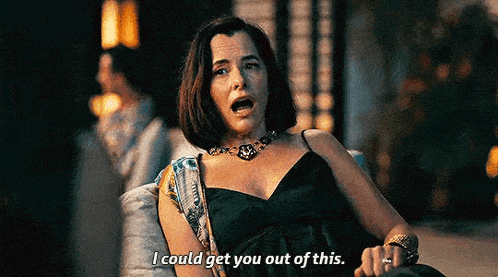 a woman in a black dress is sitting on a couch talking to someone .