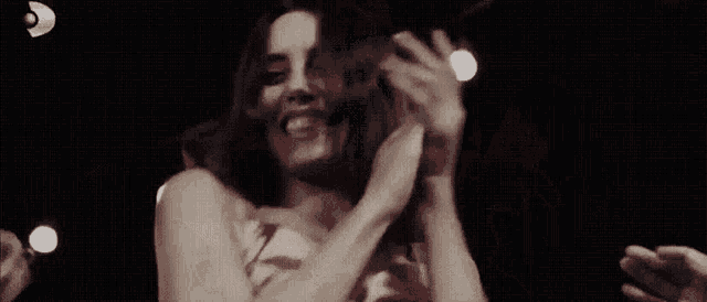 a woman is smiling and dancing in a dark room .