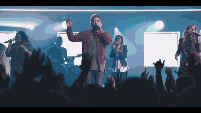 a group of people singing in front of a crowd at a concert