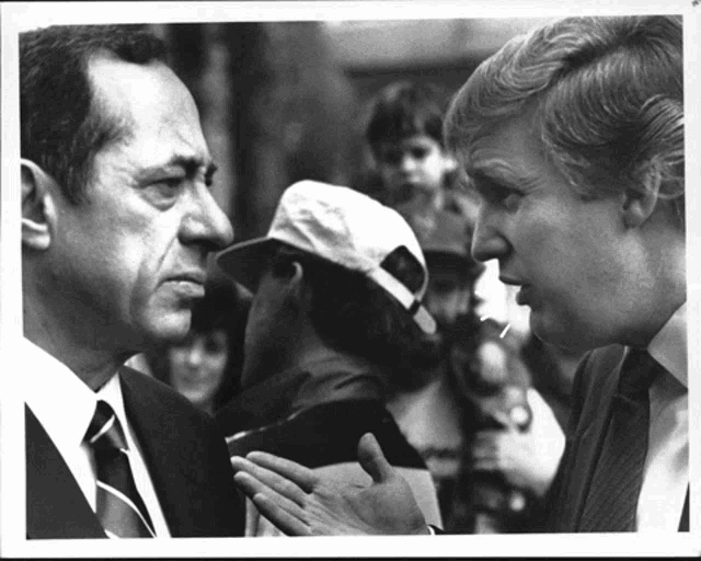 two men in suits and ties are talking to each other in a black and white photo
