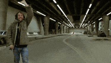 a man in a green jacket is waving his hand