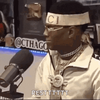 a man wearing a headband with the word gucci on it is talking into a microphone .