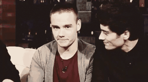 two young men are sitting next to each other on a couch smiling .