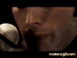 a man is singing into a microphone in a close up of his mouth .