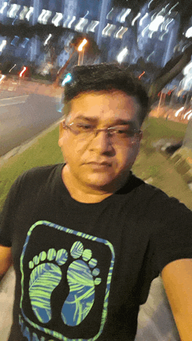 a man wearing glasses and a black shirt with a footprint on it