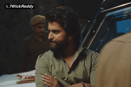 a man with a beard is standing in front of a sign that says x7wickreddy