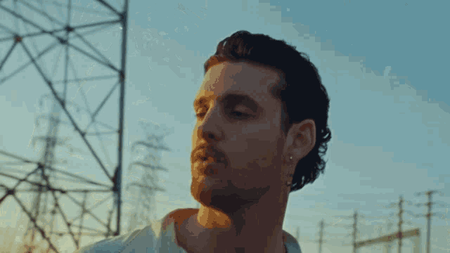 a man with a beard is standing in front of a power line