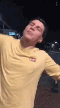a man in a yellow shirt is making a funny face .
