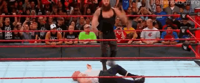 a wrestling match is taking place in a ring in front of a crowd .