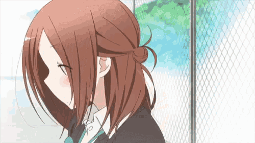 a girl with red hair is standing next to a fence .