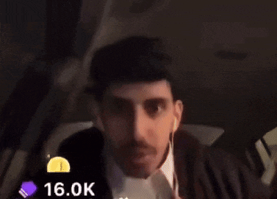 a man is sitting in the back seat of a car wearing ear buds .