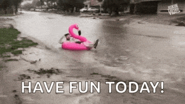 a man is floating on a pink flamingo raft in a flooded street .