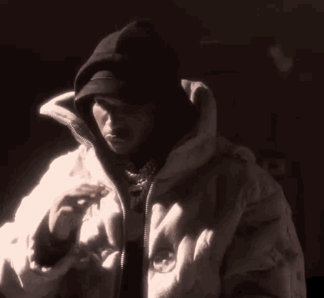a man wearing a hat and a white jacket is standing in the dark .