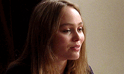 a close up of a woman 's face with long hair and a dark background .