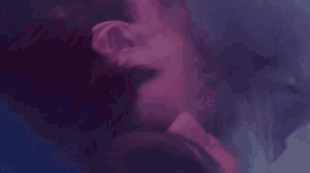 a man is holding a woman 's hand in a purple light .