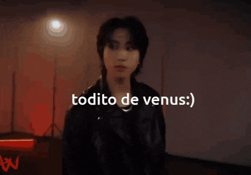 a man in a leather jacket is standing in a dark room with the words todito de venus written above him