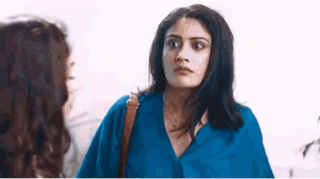 a woman in a blue shirt is looking at another woman in a blue shirt .