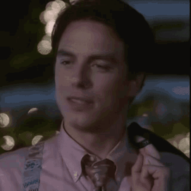a man in a pink shirt and tie is talking on a cellphone