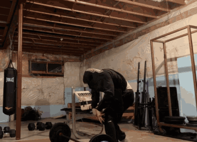 a man squatting in a gym with a everlast punching bag in the background