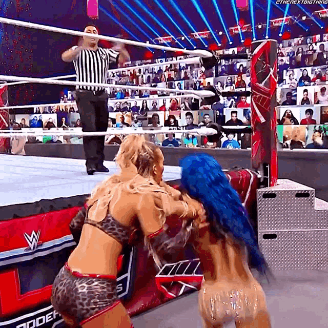 two women are wrestling in a wrestling ring with a referee watching