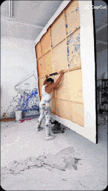 a man is holding a large piece of wood in front of a wall that says capcut in the corner