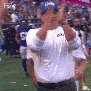 a man wearing a seahawks hat and a white shirt is giving a thumbs up