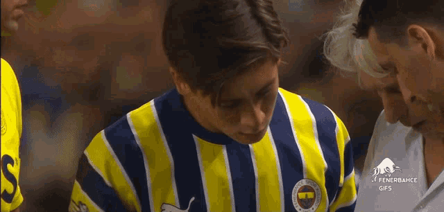 a man wearing a yellow and blue striped shirt with the word fenerbahce on the front