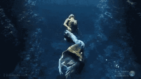 a mermaid is swimming in the ocean with her tail visible