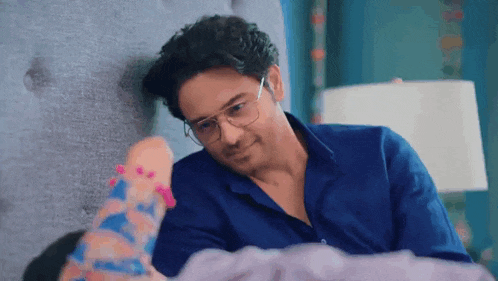 a man wearing glasses is laying on a bed next to a woman .