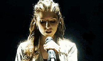 a woman singing into a microphone in a dark room