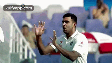 a man in a white shirt is making a funny face while playing a game of cricket .