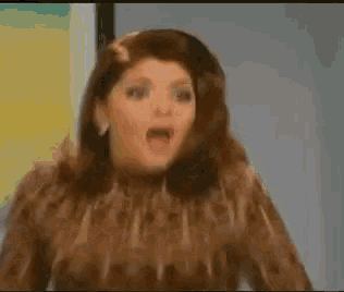 a woman in a leopard print shirt is standing in a hallway with her mouth open
