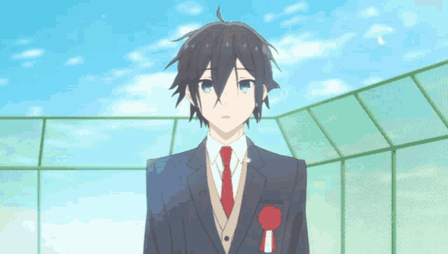 a boy in a suit and tie with a red ribbon around his neck