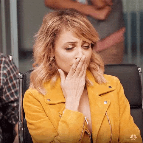 a woman wearing a yellow jacket is covering her mouth with her hand .