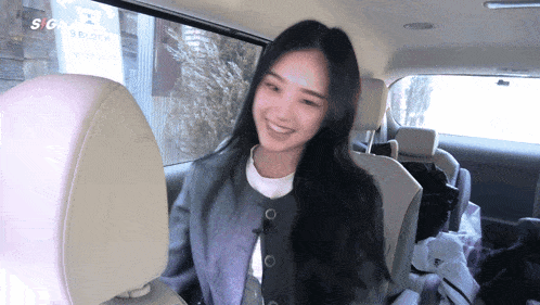 a woman sits in the back seat of a car with a sign that says sg