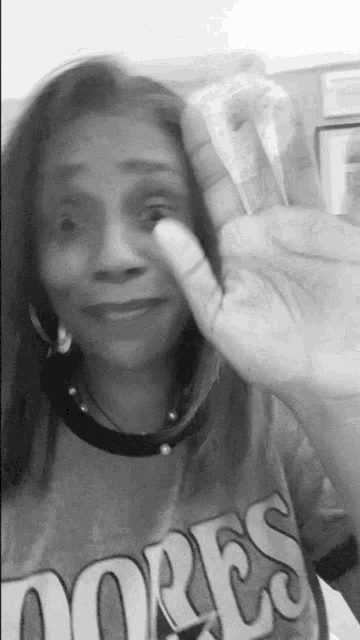 a woman is waving her hand in a black and white photo while wearing a t-shirt that says ores .