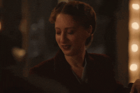 a woman in a dark room is smiling and looking down