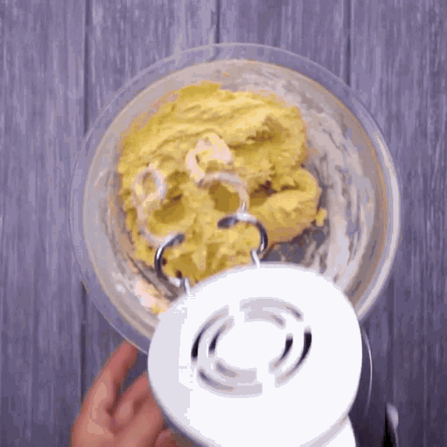 a person is holding a mixer over a bowl of batter ..